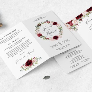 May include: A wedding invitation suite with a floral design. The front of the invitation features a wreath of burgundy and blush pink flowers with greenery. The text "Jessie and Richard" is written in a script font. The back of the invitation includes the wedding date, time, and location. The ceremony card lists the order of events for the wedding ceremony.