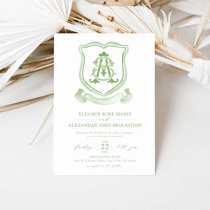 May include: A white invitation card with a green crest design. The crest features intertwined initials and a banner. The text includes names, a date, time, and location for an evening reception. The card is decorated with a watercolor style.