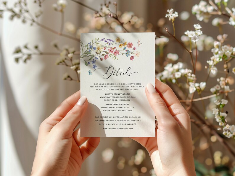 May include: A white card with a floral design and the word "Details" in cursive. The card provides hotel information for a wedding, including the hotel names, websites, and group codes. The text also includes a website address for additional information.