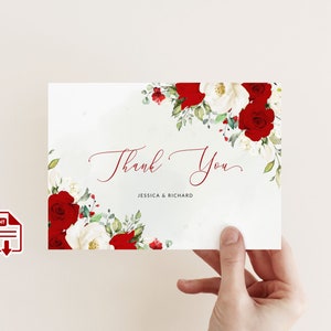 K&ouml;nnte beinhalten: Eine wei&szlig;e Karte mit roten und wei&szlig;en Rosen und gr&uuml;nem Laub. Die Worte "Thank You" sind in einer Schreibschrift geschrieben, darunter die Namen "Jessica & Richard". Die Karte wird von einer Hand gehalten.