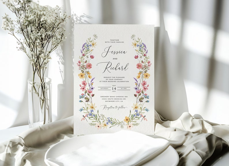 May include: A floral wedding invitation with a wreath of watercolor flowers in shades of pink, yellow, blue, and green. The invitation reads "Jessica and Richard" and includes the date, time, and location of the wedding.