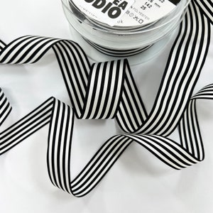 May include: Black and white striped ribbon measuring 25 mm wide. The ribbon is made from polyester and is packaged on a spool.