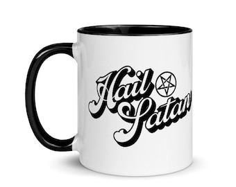 May include: White ceramic coffee mug with a black rim and handle. The mug features a black graphic that says "Hail Satan" with a pentagram symbol.