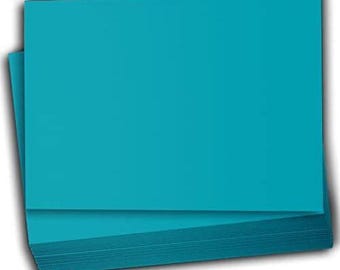 May include: A stack of teal cardstock paper. The paper is smooth and has a slight sheen.