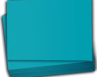May include: A stack of turquoise-colored paper sheets. The top sheets are a solid, flat color, while the edges of the stack reveal the layered structure. The paper has a smooth texture and a slight sheen, suggesting a high-quality finish.