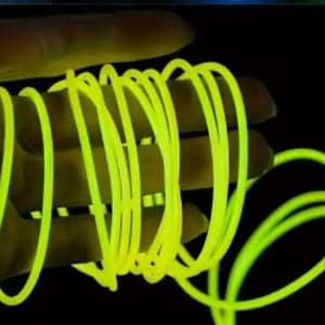 Peut inclure: Une main tenant un cordon jaune néon enroulé sur un fond noir. Le cordon brille vivement, suggérant qu'il pourrait être fluorescent ou éclairé. L'image met en évidence la texture et la couleur du cordon.