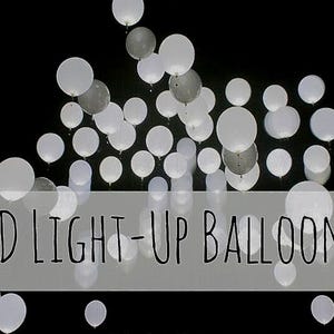 Puede incluir: Un grupo de globos LED blancos y grises iluminados sobre un fondo negro. Los globos son redondos y parecen flotar. El texto "LED LIGHT-UP BALLOONS" se muestra en un rectángulo blanco en la parte inferior de la imagen.