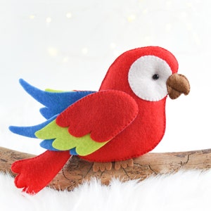 May include: A red, blue, and green felt parrot with a white eye perched on a branch.