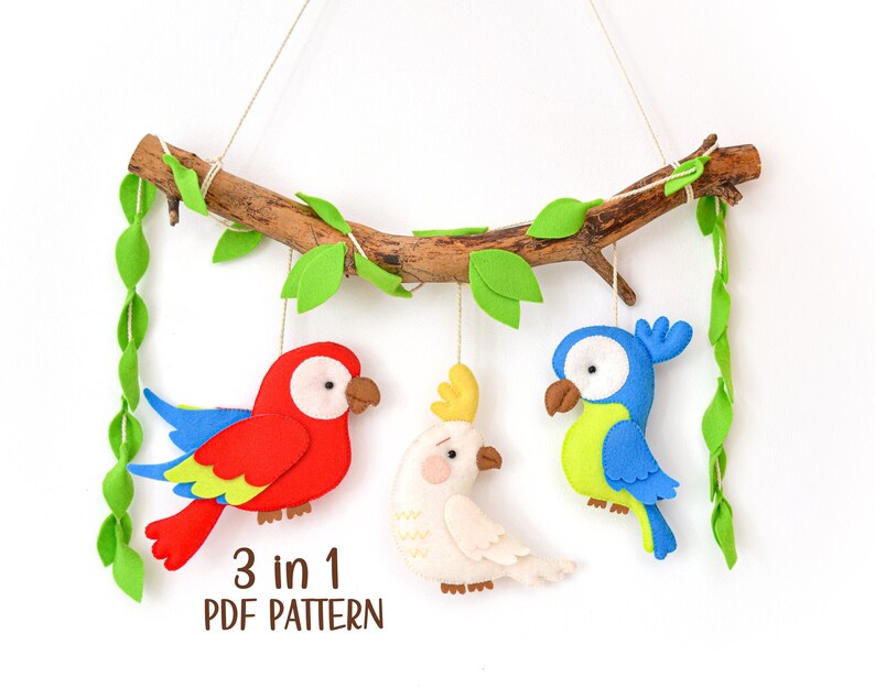 May include: A 3 in 1 PDF pattern for sewing a felt parrot, cockatoo, and bluebird hanging mobile. The birds are hanging from a branch with green felt leaves.