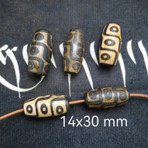 May include: Five brown and black agate beads with a geometric pattern. The beads are strung on a brown leather cord. The beads measure 14x30 mm.