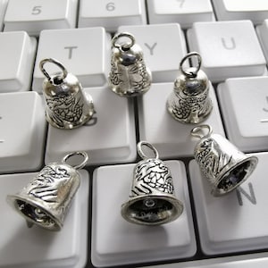 May include: Six silver bells with a dragon design on a white keyboard. The bells have a loop at the top for hanging.