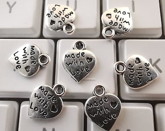 May include: Six silver heart-shaped charms with the text "Made with Love" on each charm. The charms have a small loop at the top for attaching to a necklace or bracelet.