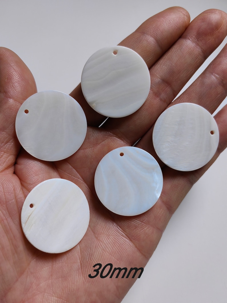May include: Five white round mother of pearl shell discs with a hole in the center. Each disc is approximately 30mm in diameter.