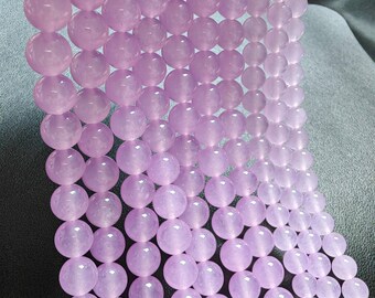 Puede incluir: Una hebra de cuentas redondas de color morado claro. Las cuentas son lisas y tienen un ligero brillo.