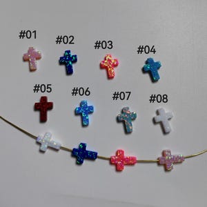 Puede incluir: Diez dijes de cruz de ópalo en varios colores, incluyendo blanco, azul, rosa, rojo e iridiscente. Los dijes están numerados del 01 al 08.