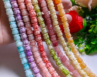 May include: Strands of colorful tulip-shaped beads in various pastel shades. The beads are strung together, creating a vibrant and decorative element. The beads are approximately 0.5 inches in diameter.