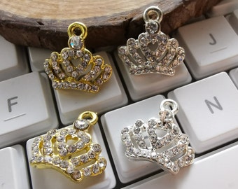 May include: Four silver and gold crown charms with clear rhinestone accents. The charms are on a white keyboard with black keys.