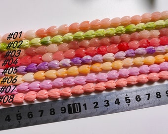 May include: A close-up of eight rows of colorful flower-shaped beads. The beads are arranged in rows, with each row a different color. The colors are: light green, light pink, pink, purple, orange, light pink, pink, and coral. The beads are all about 1 cm in diameter. A ruler is visible at the bottom of the image, with numbers 3 through 10 visible.