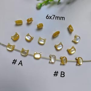 May include: A close-up of two strands of iridescent yellow cat-shaped beads. The beads are 6x7mm in size. The first strand is labelled #A and the second strand is labelled #B.