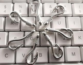 May include: Seven silver-colored hooks arranged in a circle on a white keyboard. The hooks are all the same size and shape, and they are all facing the same direction.