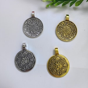 May include: Four silver and gold pendants with intricate designs. The pendants feature a circular shape with a raised center and a detailed border. The designs include a mandala, a symbol of the universe, and a symbol of the Om mantra.