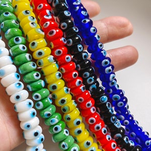 May include: A set of six strands of colorful glass beads with an evil eye design. The beads are white, green, yellow, red, black, and blue.