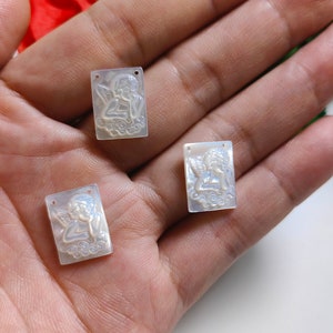 Puede incluir: Tres abalorios rectangulares de nácar blanco con un diseño de querubín tallado. Cada abalorio tiene dos agujeros para sujetarlo a joyas.