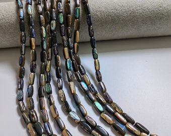May include: A strand of iridescent abalone shell beads in a rectangular shape. The beads are a dark brown color with hints of green, blue, and gold.