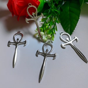 May include: Four silver Ankh pendants with a loop at the top for attaching to a chain. The Ankh is an ancient Egyptian symbol of life.