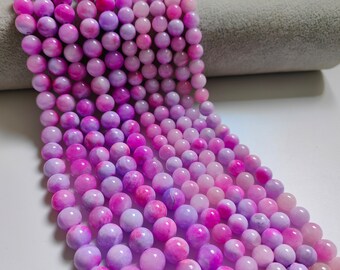 Puede incluir: Una hebra de cuentas de piedras preciosas rosas y moradas. Las cuentas son redondas y tienen un aspecto marmoleado.