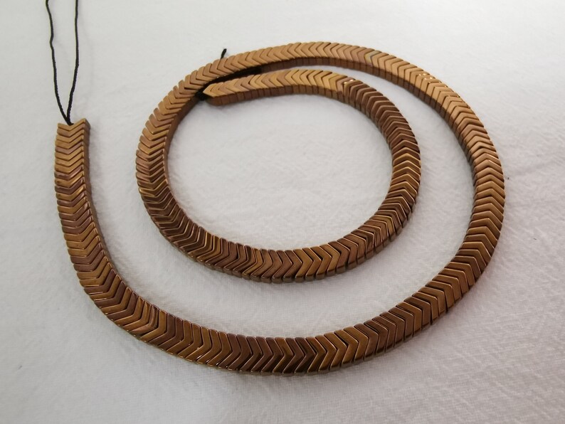 May include: A strand of brown chevron-shaped hematite beads with a black cord.