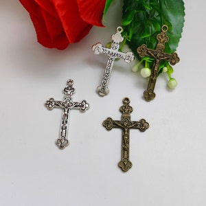 May include: Four silver and bronze cross charms with intricate details. The crosses feature a figure of Jesus Christ on the front.