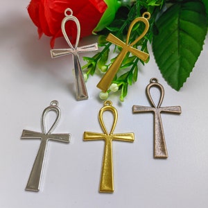 Puede incluir: Cinco colgantes Ankh de plata, oro y bronce con un bucle en la parte superior para sujetar una cadena. El Ankh es un antiguo símbolo egipcio de la vida.