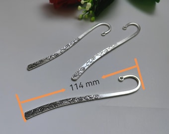 May include: Two silver metal bookmarks with a floral design. The bookmarks are 114 mm long.