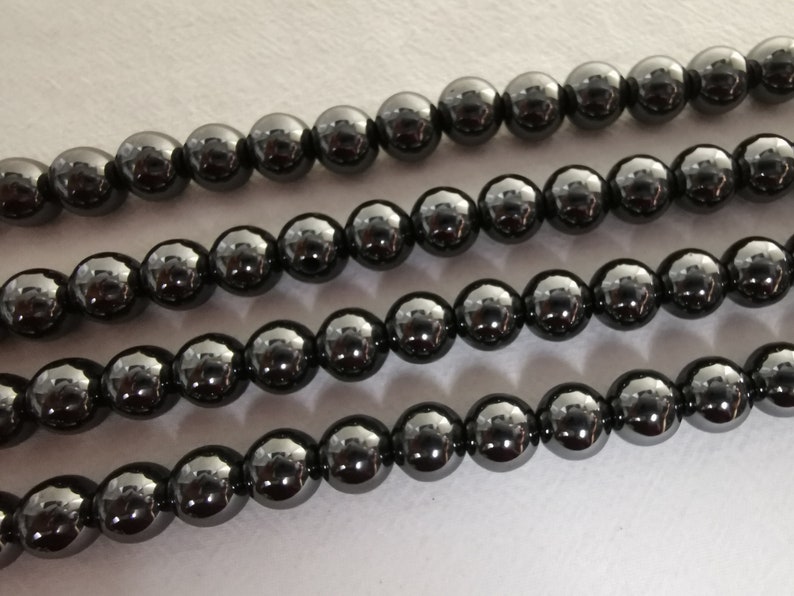 May include: A strand of black hematite beads. The beads are round and have a shiny, metallic finish.