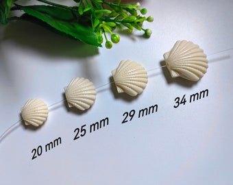 May include: Four white seashell beads of varying sizes on a white background. The beads measure 20 mm, 25 mm, 29 mm, and 34 mm.