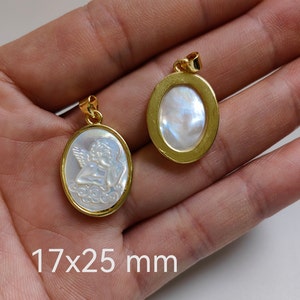 May include: Two gold oval pendants with a white mother of pearl inlay. One pendant features a carved angel design. The pendants measure 17x25 mm.