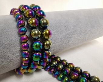 May include: A strand of iridescent rainbow colored beads, made of hematite, strung on a wire. The beads are round and have a smooth, polished finish.