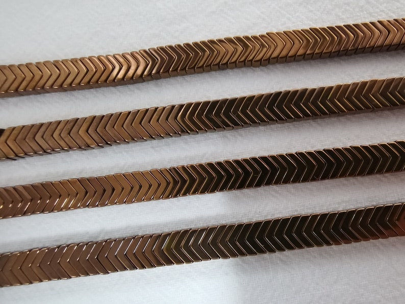May include: Four rows of brown chevron-shaped beads, each row is made of multiple beads, the beads are arranged in a zig-zag pattern.