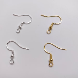 May include: Four earring hooks, two silver and two gold. Each hook has a small ball at the end.