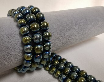 May include: A strand of iridescent blue and green glass beads. The beads are round and have a smooth, shiny finish.