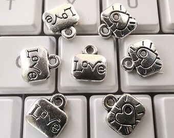 Puede incluir: Seis colgantes de plata con diferentes diseños. Los colgantes presentan la palabra "Love" y formas de corazón. Los colgantes son perfectos para la elaboración de joyas o para agregar a un llavero.