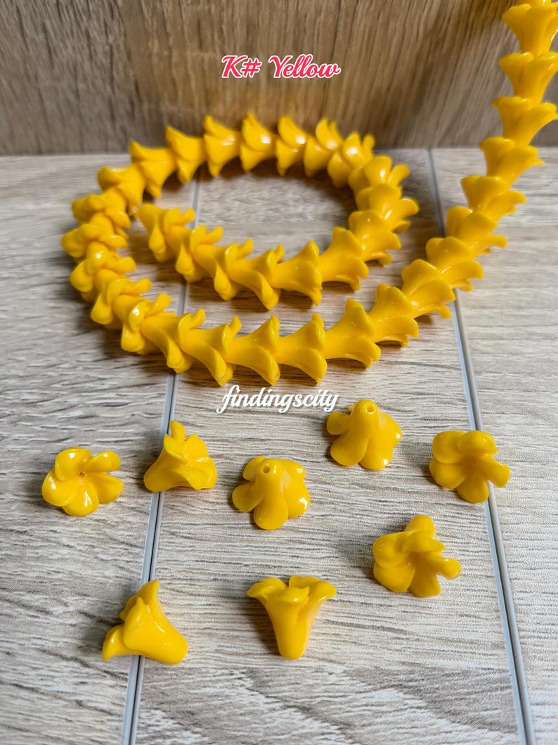 May include: A string of bright yellow flower-shaped beads arranged in a circular pattern, accompanied by several loose individual flower beads. The text K# Yellow and findingscity are visible in the image. The beads feature a five-petal design.