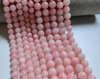 Puede incluir: Una hebra de cuentas redondas de color rosa pálido hechas de cuarzo rosa. Las cuentas son lisas y pulidas, y tienen un brillo sutil.