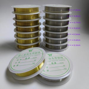 May include: Spools of gold and silver-colored copper wire for jewelry making. The wire is available in various thicknesses, ranging from 0.3mm to 1.0mm. The image also shows the packaging with the text "Special Copper Wire for Jewelry".