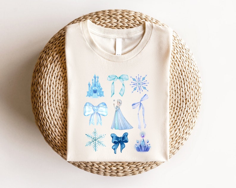 May include: A white t-shirt with a blue and white watercolor design featuring a castle, snowflakes, bows, and a princess.