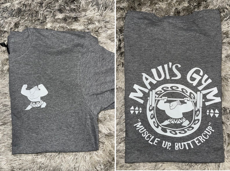 May include: A grey t-shirt with a white graphic of a cartoon character lifting a barbell. The graphic says "Maui's Gym" and "Muscle Up, Buttercup".