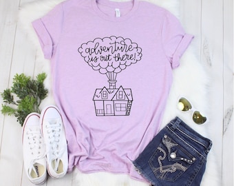 May include: A lavender t-shirt with a black graphic of a house with a cloud and the text "adventure is out there!"
