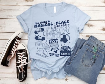 May include: Light blue t-shirt with a graphic design featuring various Disney World icons, including Cinderella's Castle, Mickey Mouse, Spaceship Earth, and the words "The Most Magical Place on Earth".
