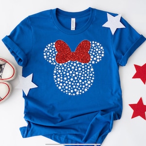 May include: A blue t-shirt with a white and red glitter Mickey Mouse head design. The design features white stars and a red bow.